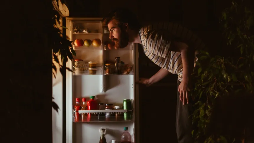 Person looking into the refrigerator late at night, illustrating how late eating can affect overnight digestion and sleep in diabetes